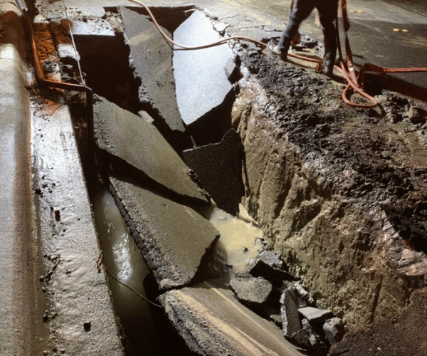 Workers at night responding to a damaged roadway trench.